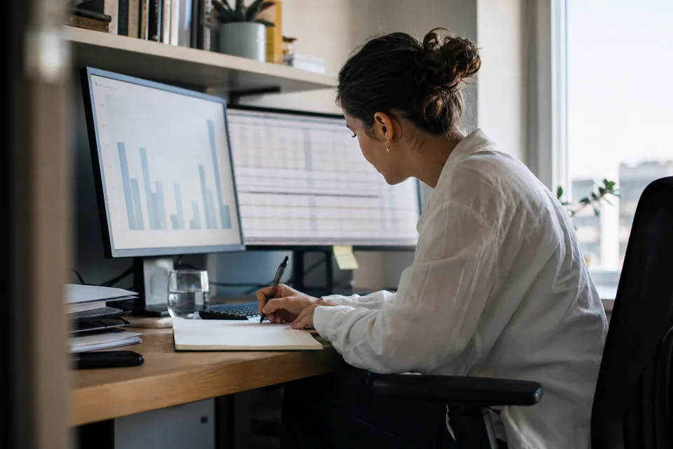 Analyst comparing domain sales data on two monitors
